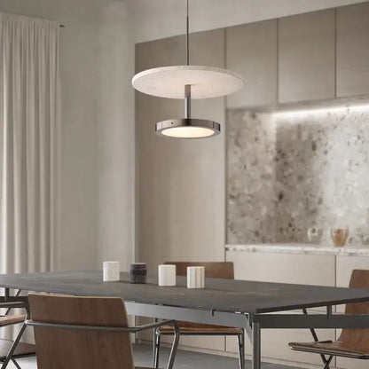 Modern matte white and brushed metal led chandelier black stone pendant suspended above a dining table by decorbites