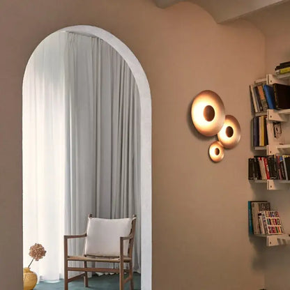 Three warm-toned brass ginger round wall lamps with concentric rings for modern matte white and brushed bronze decorbites