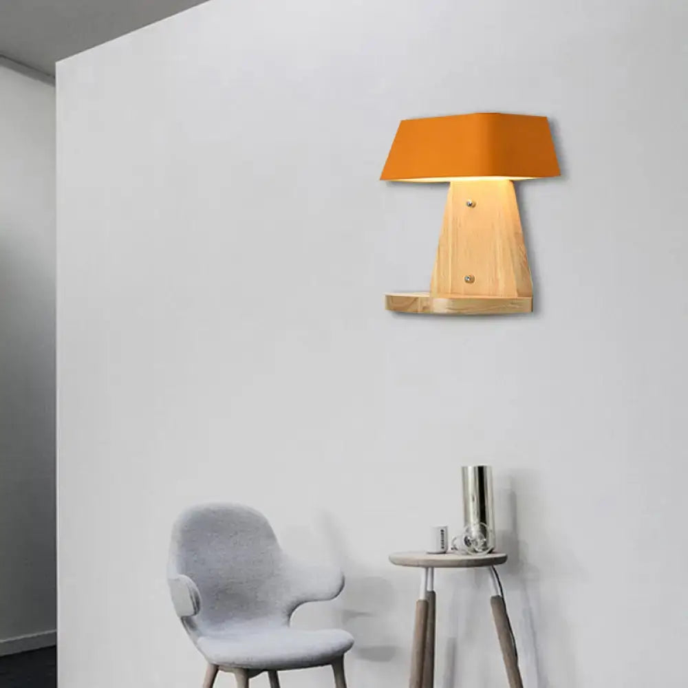 Modern metal light fixture with orange lampshade mounted on wooden backplate with small shelf for living room