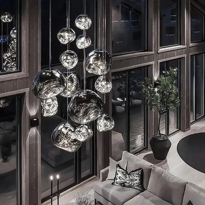 Modern metallic glass pendant lights with reflective finish hang in an elegant dining room cluster fixture