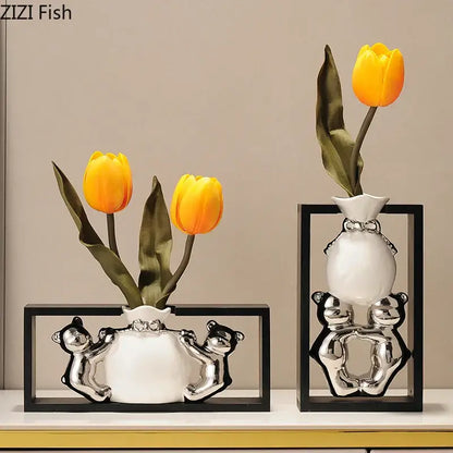 Modern metallic oval white ceramic vase with silver bear figurines holding yellow artificial flowers decorbites elegant square