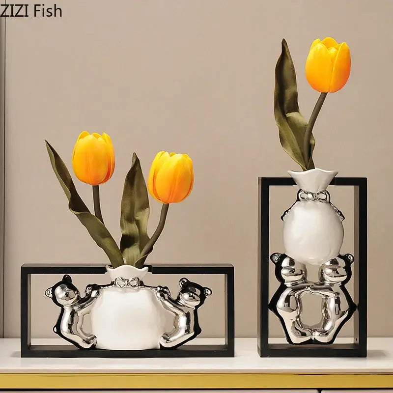 Modern metallic oval white ceramic vase with silver bear figurines holding yellow artificial flowers decorbites elegant square