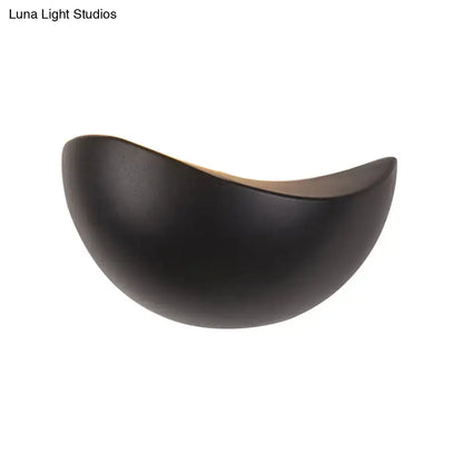 Black ceramic wall sconce with smooth curved crescent shape and warm interior for modern metallic wall washer light