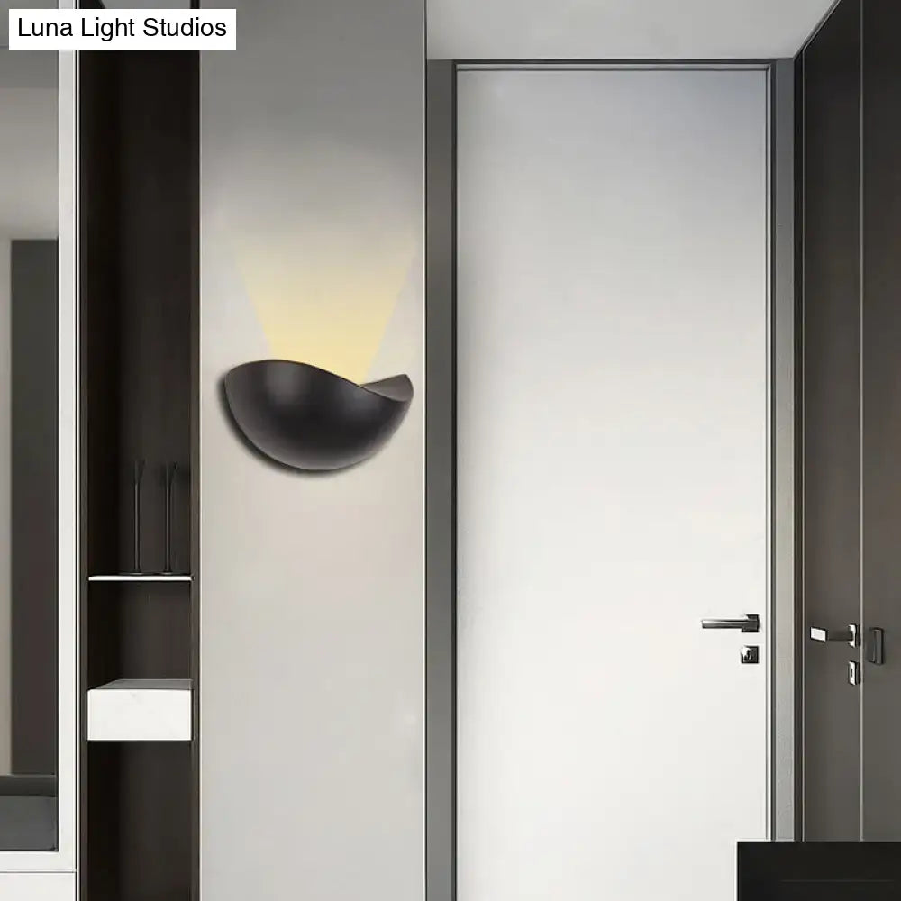 Black matte ceramic wall sconce with a sleek bowl design used as a modern metallic wall washer light for bedrooms