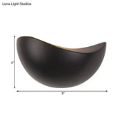 A sleek matte black ceramic bowl with a crescent shape used in modern metallic wall washer bedroom sconce lighting