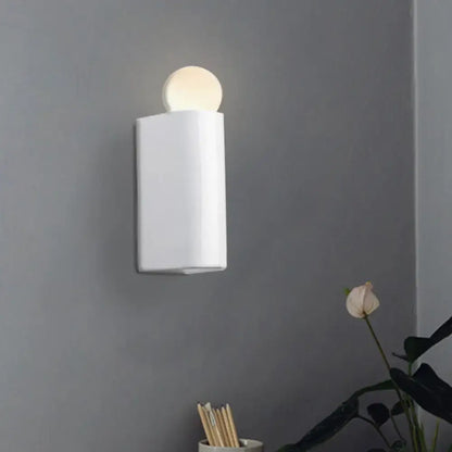 White cylindrical wall lamp with a milk glass spherical light fixture suitable for small medium bedroom spaces