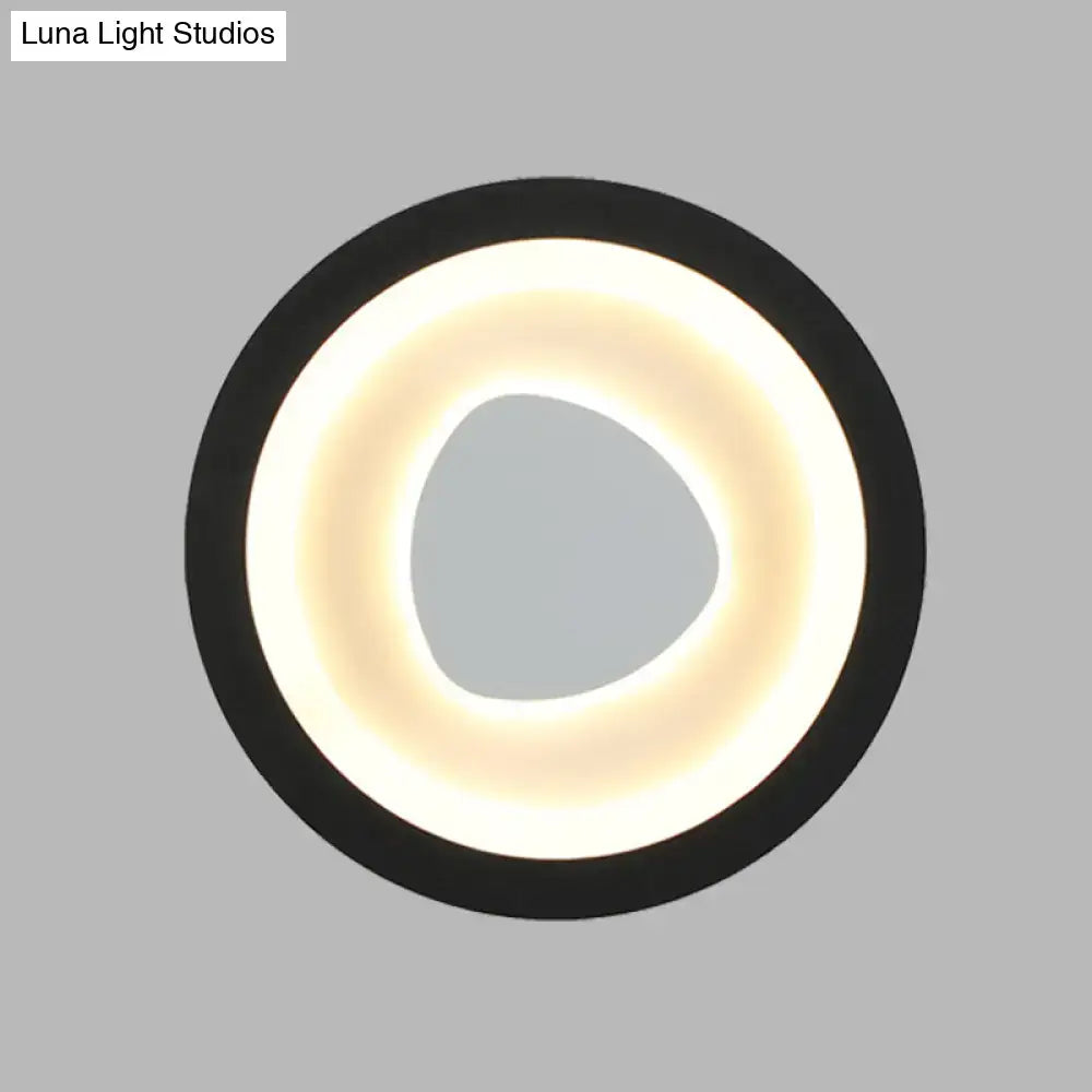 Modern minimalist black wall light with acrylic shade featuring a glowing warm white ring and irregular central opening