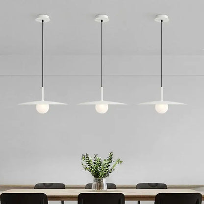 Three minimalist white pendant lights with frosted glass globes and black cords in decorbites flying saucer chandelier