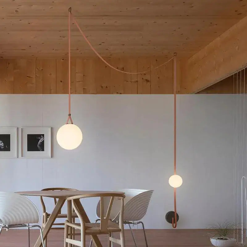 Modern minimalist frosted glass ball pendant light with warm glow and copper-toned cords for dining room decorbites glass ball