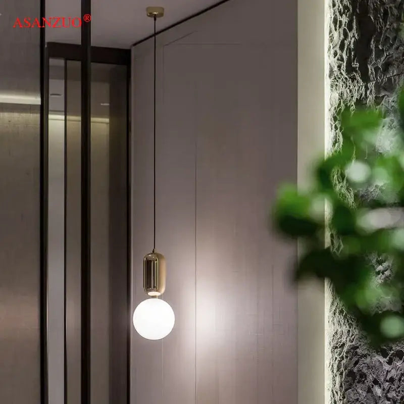 Gold-toned pendant lamp with sleek cylindrical fixture and frosted glass globe bulb for modern minimalist decorbites glass ball led