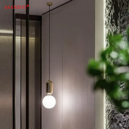 Gold-toned pendant lamp with sleek cylindrical fixture and frosted glass globe bulb for modern minimalist decorbites glass ball led