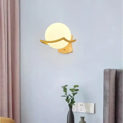 Modern minimalist wall lamp with gold-toned curved arms and a frosted white glass shade for bedroom use
