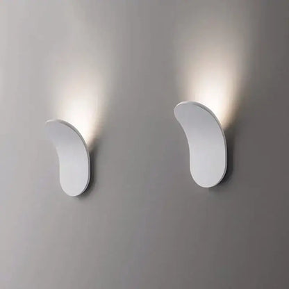 Modern minimalist gold and black led wall lamps with sleek curved white sconces emitting warm light for living room