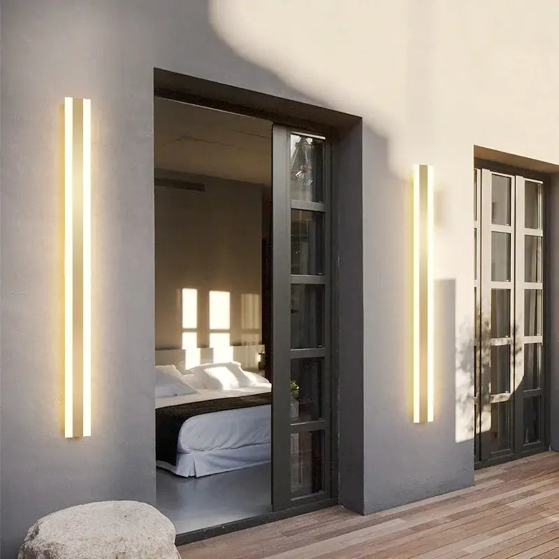 Modern minimalist gold led outdoor wall sconce with sleek vertical rectangular design emitting warm golden glow by decorbites