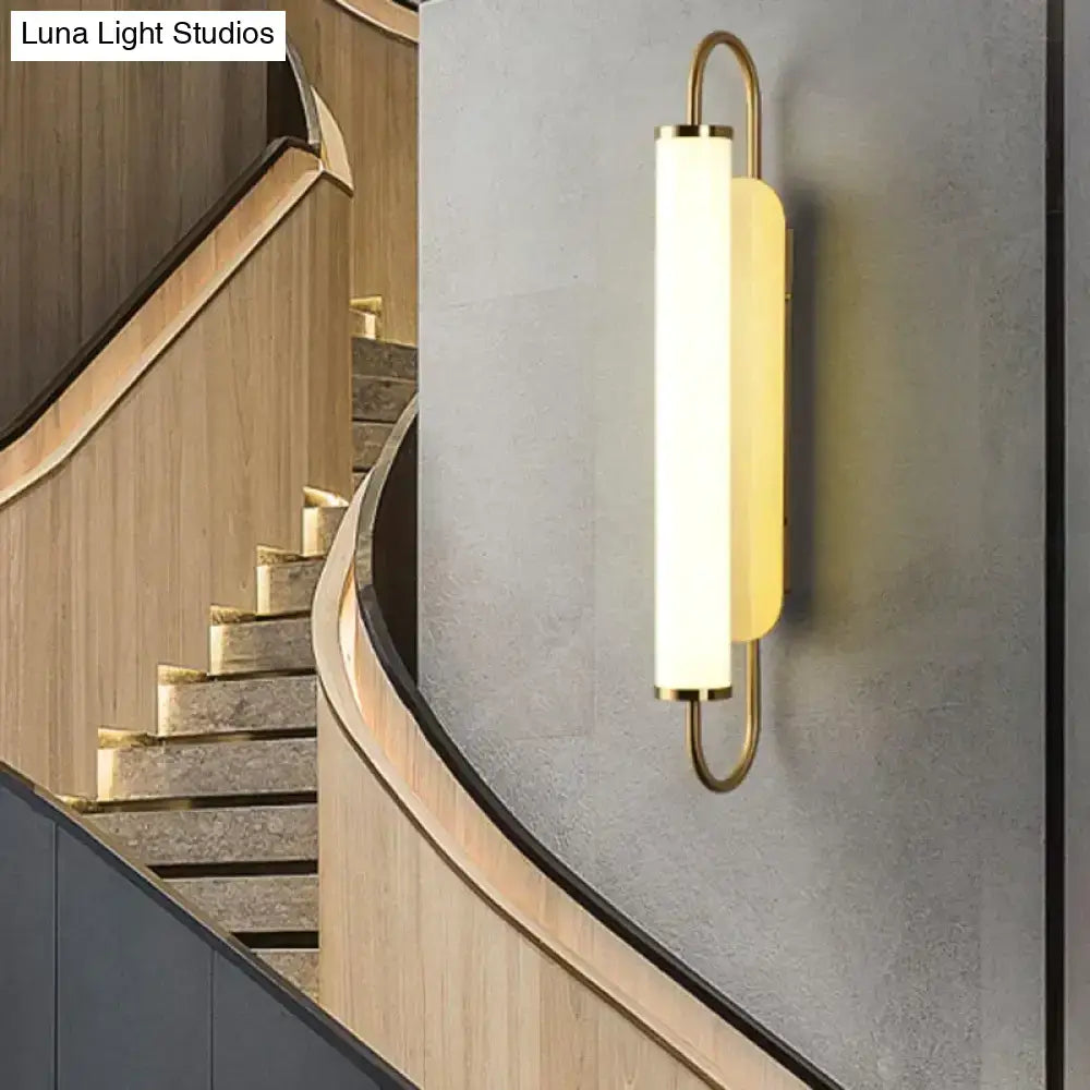 Modern minimalist gold led wall lamp with brass finish and frosted glass diffuser emitting warm light for bedroom use