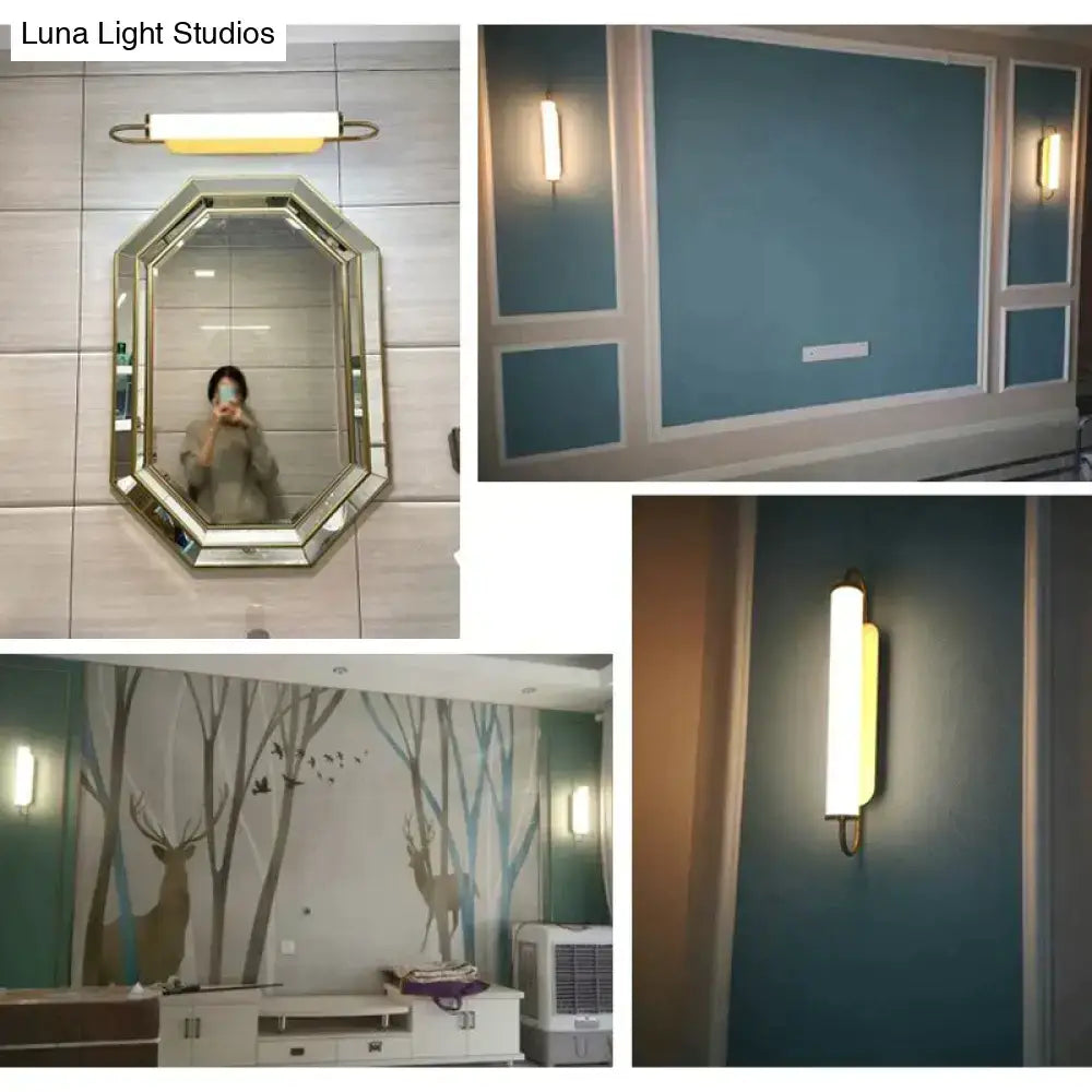 A sleek cylindrical led wall lamp with brass finish and warm yellow diffuser for modern minimalist bedroom use