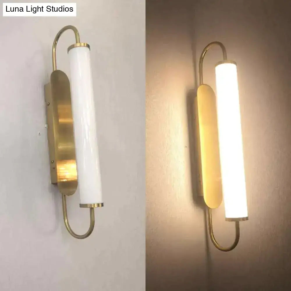 Modern minimalist gold led wall lamp with frosted glass cylindrical shade and curved brass accents for bedroom use