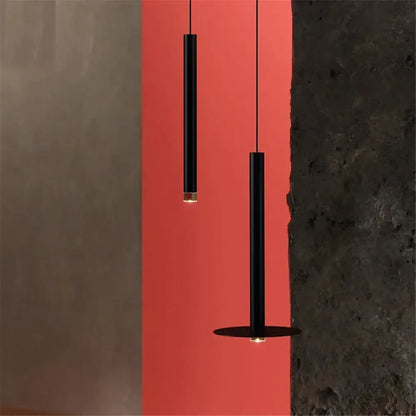 Two minimalist black cylindrical pendant lights with gold tube led accents against a vibrant red wall for kitchen decorbites gold tube