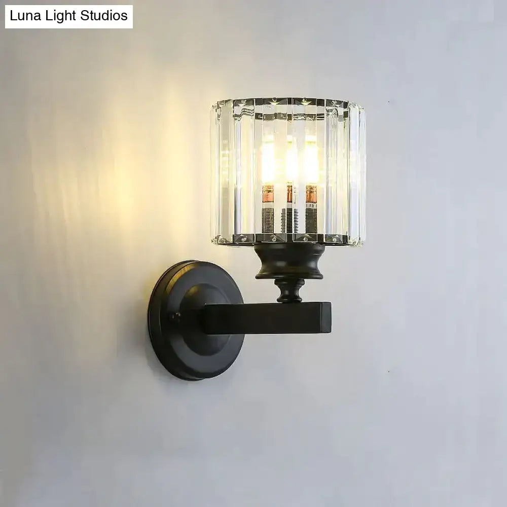 Black metal modern minimalist wall sconce with faceted crystal glass shade and three illuminated bulbs for bedroom use