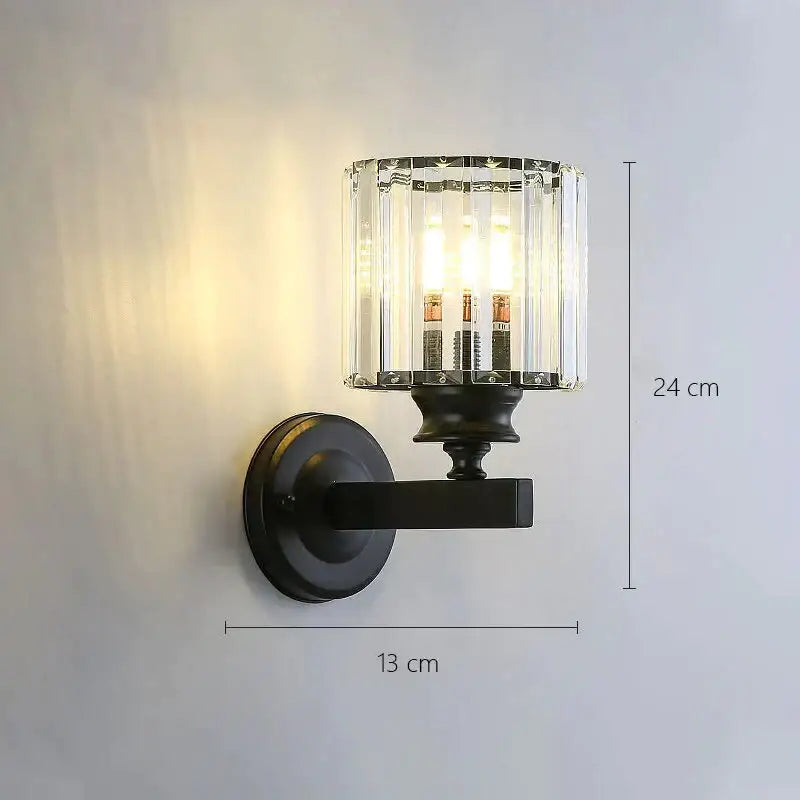 Modern minimalist black metal wall sconce with cylindrical crystal glass shade for bedroom lighting