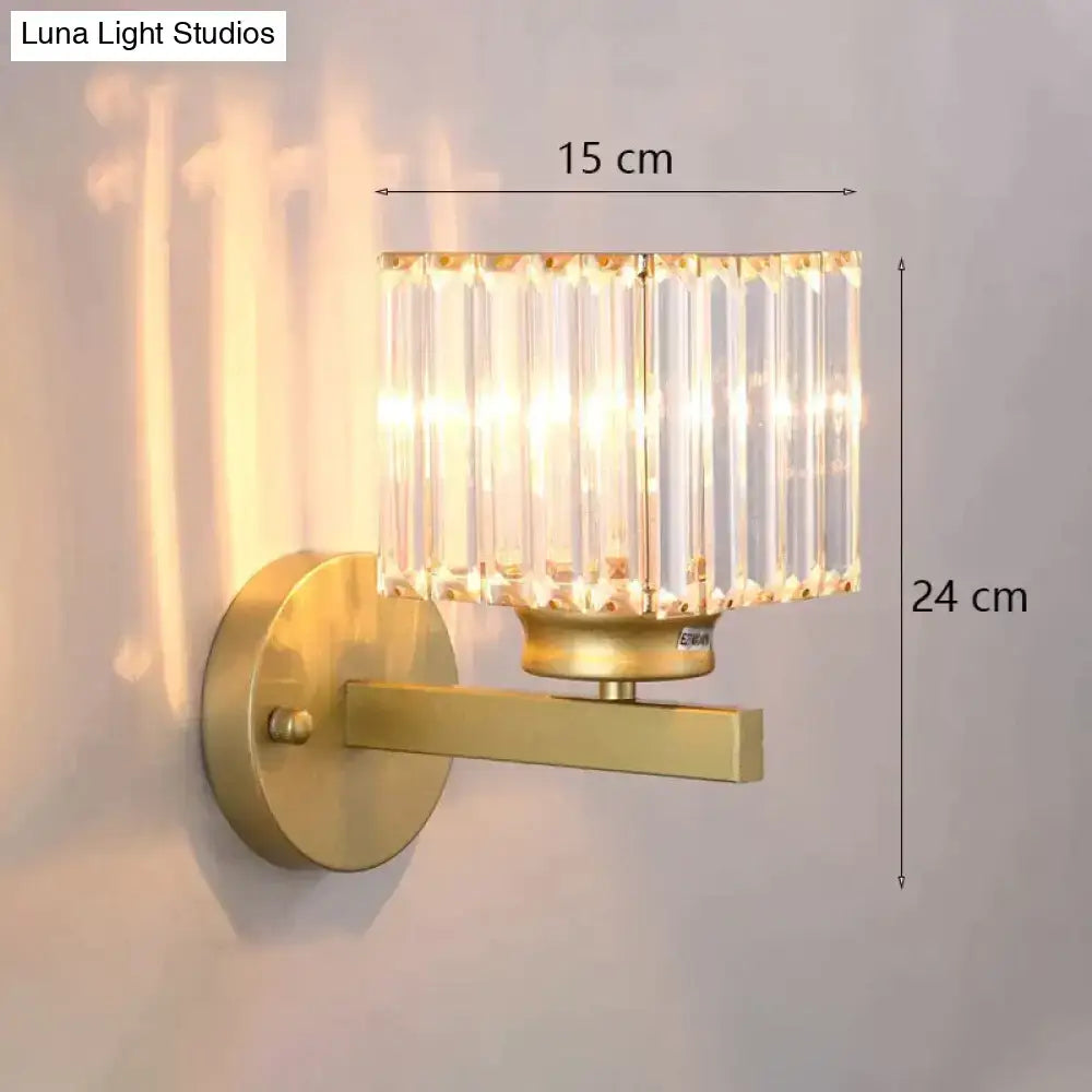 Modern minimalist gold wall lamp with a cylindrical crystal shade made of vertical glass rods for bedroom use