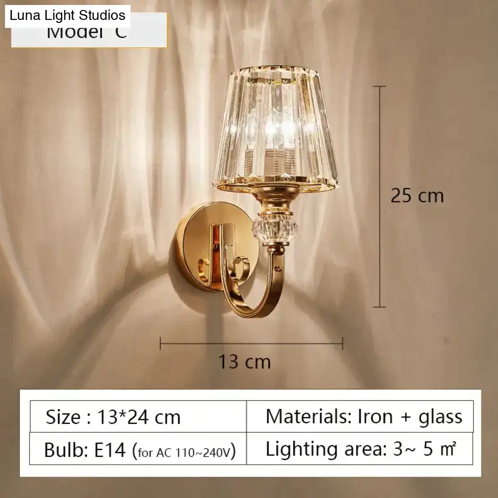 Modern minimalist wall sconce gold toned with faceted crystal glass shade and decorative accents for bedroom lighting