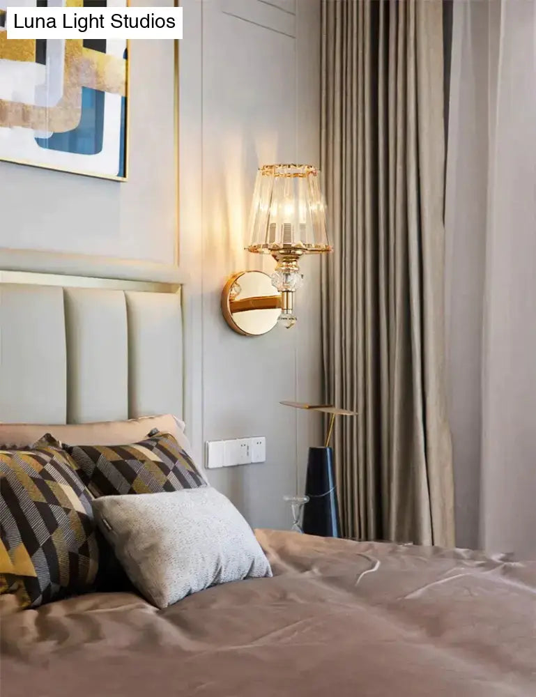 Modern minimalist wall sconce in gold tone with crystal-encrusted base and tiered translucent glass shade for bedroom
