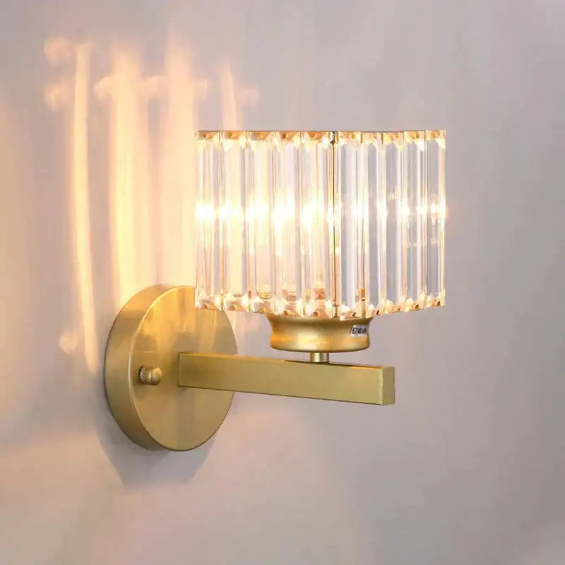Modern minimalist gold wall lamp with rectangular crystal shade made of vertical faceted glass rods for bedroom use