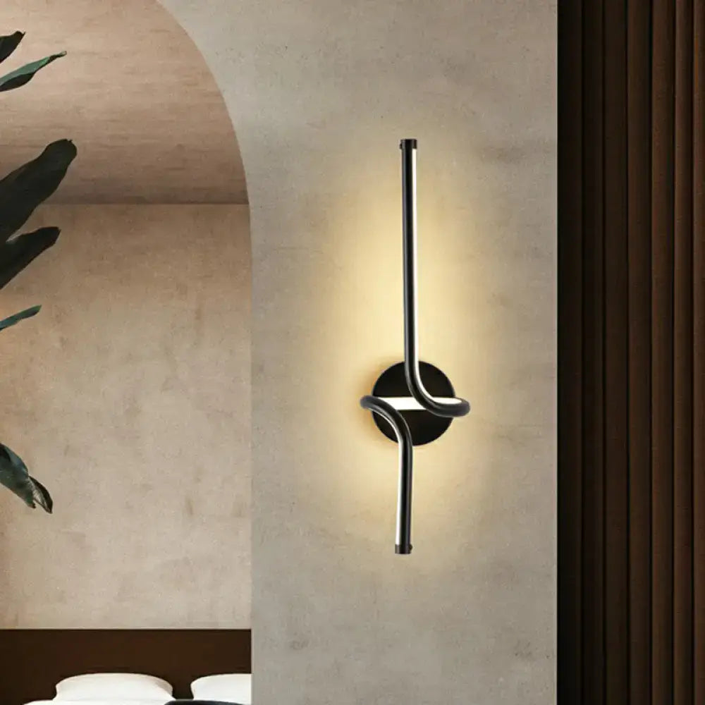 Modern minimalist black metallic led wall sconce with sleek curved design providing warm ambient bedroom lighting