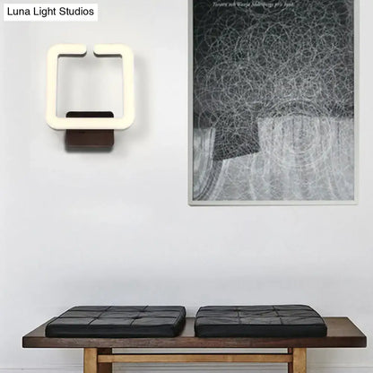 Modern off-white square LED wall sconce with dark wood base providing warm white natural light for bedroom use
