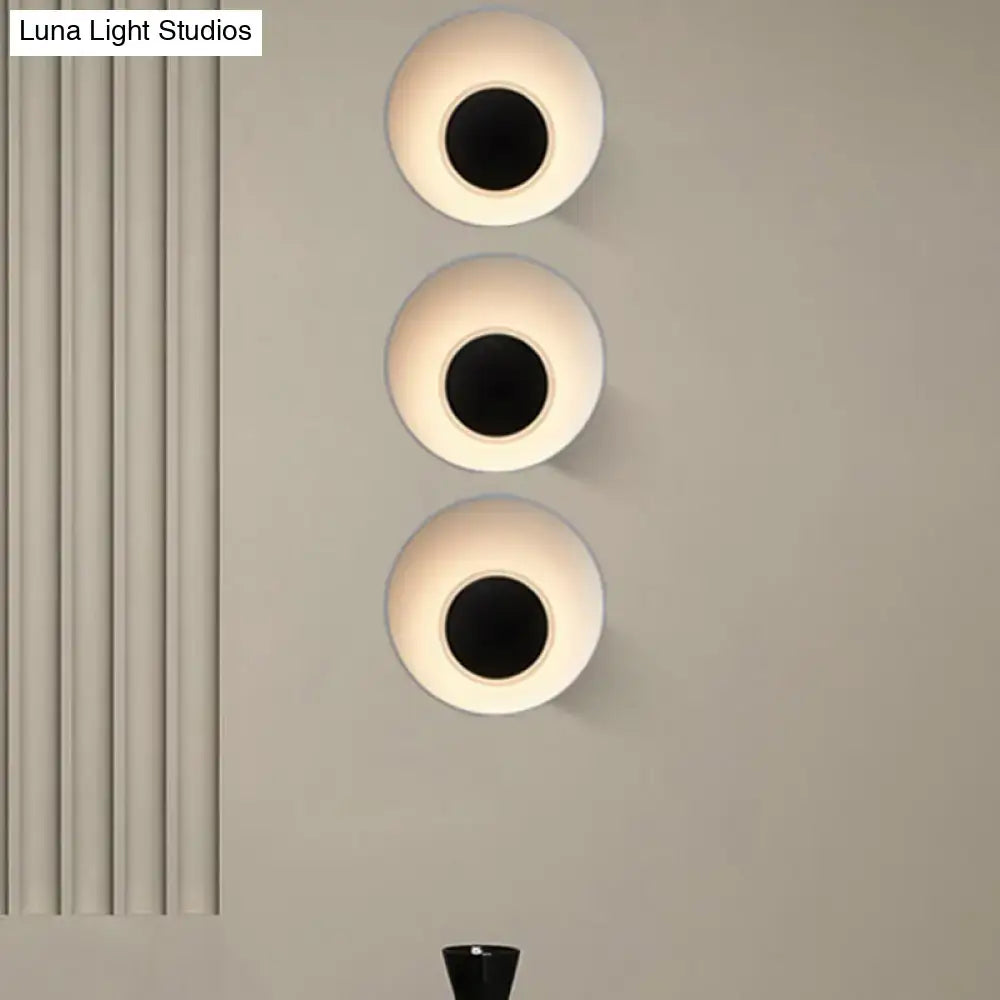 Three modern minimalist wall lamps with circular matte white finish and black central openings for living room use