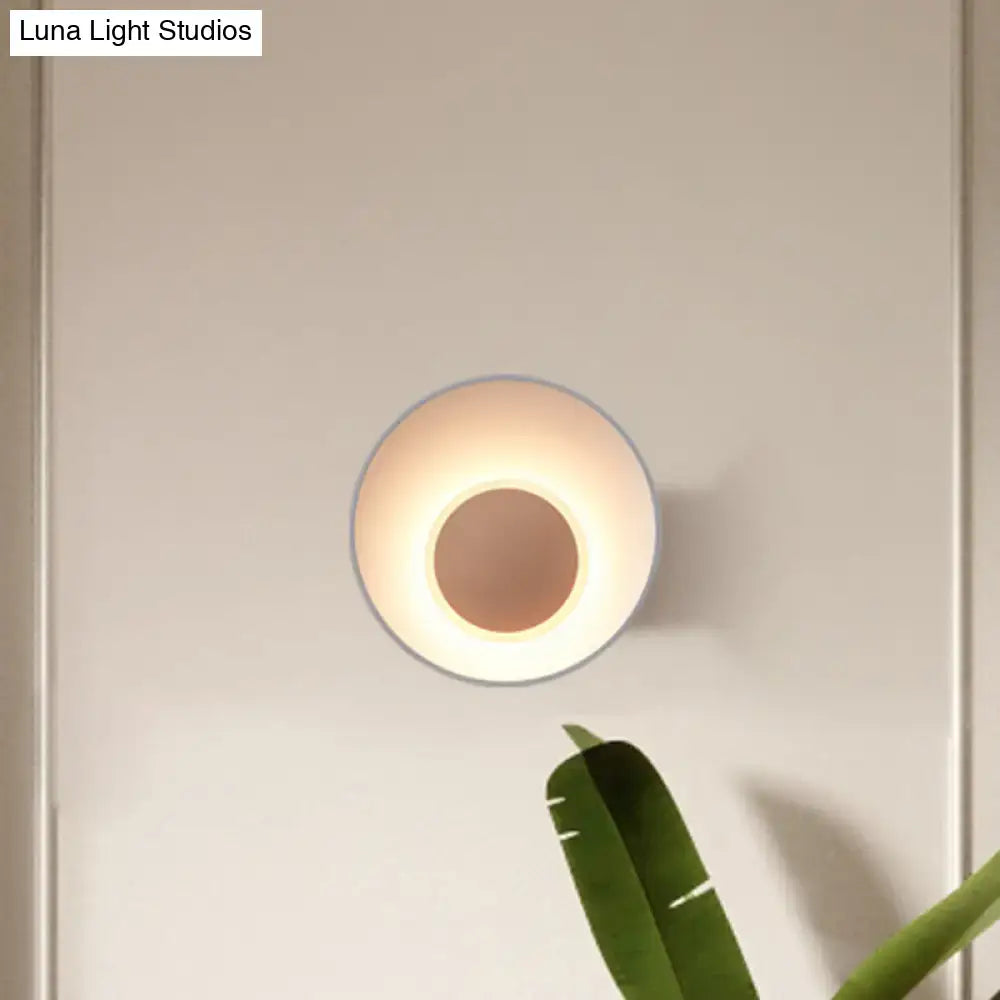 Minimalist circular wall lamp with warm glow and sleek metallic finish for modern white and black living room sconce
