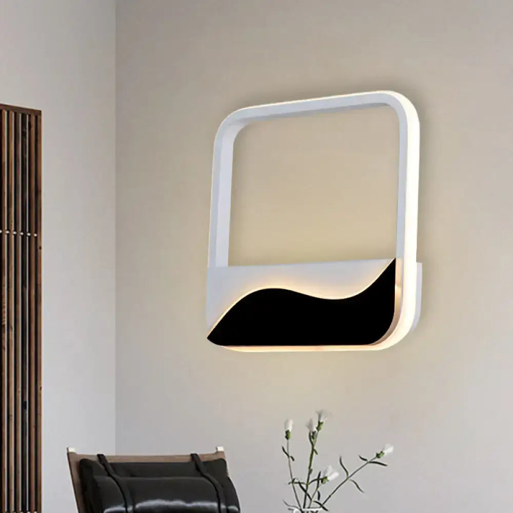 Modern white and black led wall mount sconce with sleek minimalist design and curved lower section providing warm white light