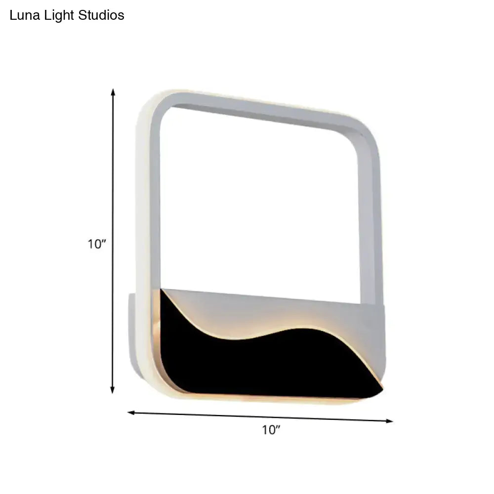 Modern minimalist white and black led wall mount sconce with sleek frame and wave-shaped panel emitting warm white light