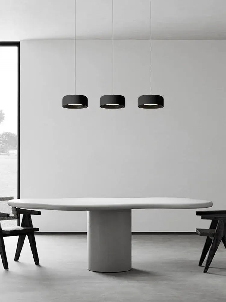 Three sleek black cylindrical pendant lights in a modern minimalist dining space by decorbites designer led chandelier
