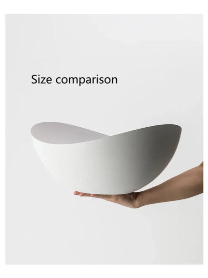 A sleek white ceramic bowl with a curved asymmetrical design complementing decorbites ingot ceiling lamp decor