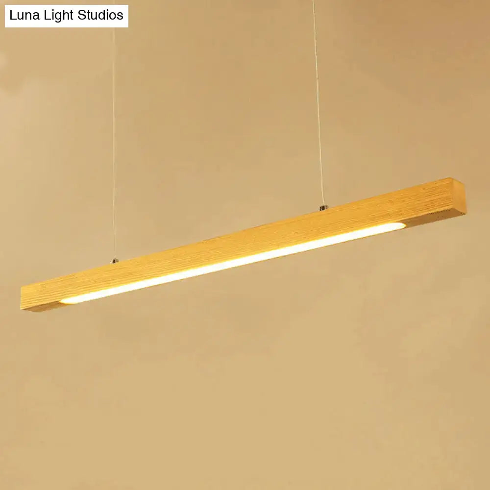 A sleek rectangular wooden linear island pendant light with warm glow and visible wood grain for kitchen use