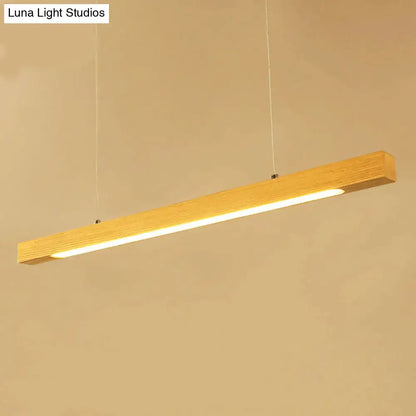 A sleek rectangular wooden linear island pendant light with warm glow and visible wood grain for kitchen use
