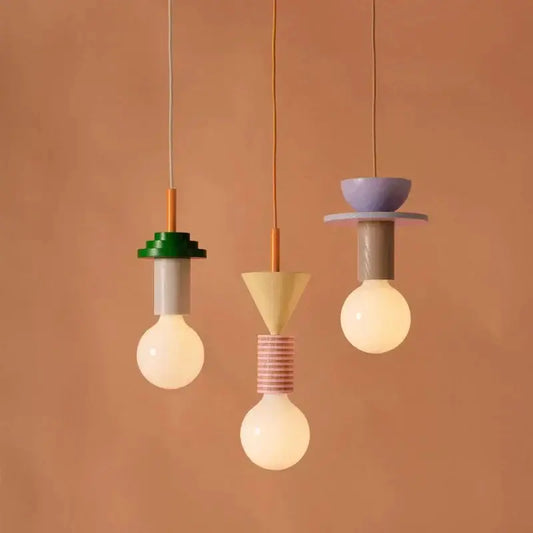 Three modern multi color wood and iron accent cord pendant lights with geometric tops and exposed bulbs for kitchen dining room