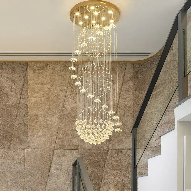 A luxurious gold-toned modern multi tiered crystal hanging loft chandelier with cascading crystal droplets and flower accents