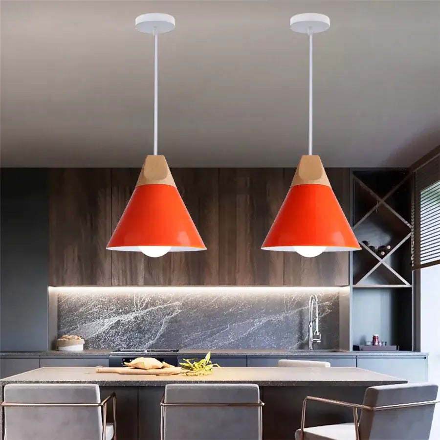 Two vibrant orange decorbites cone wood pendant lights with wooden tops hang in a modern kitchen setting