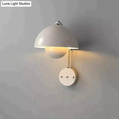 A sleek white ceramic wall lamp with dome-shaped shade and brass base type finish for modern bedroom decor