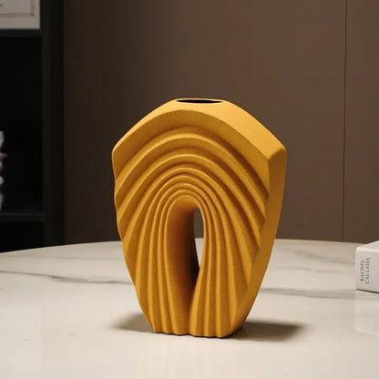 A modern mustard yellow ceramic vase with geometric folds and concentric ridges for stylish living room decor