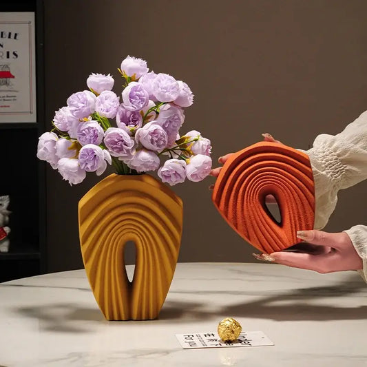 A modern mustard yellow geometric folds ceramic vase with sculpted arch design holds light purple roses for decorbites decor