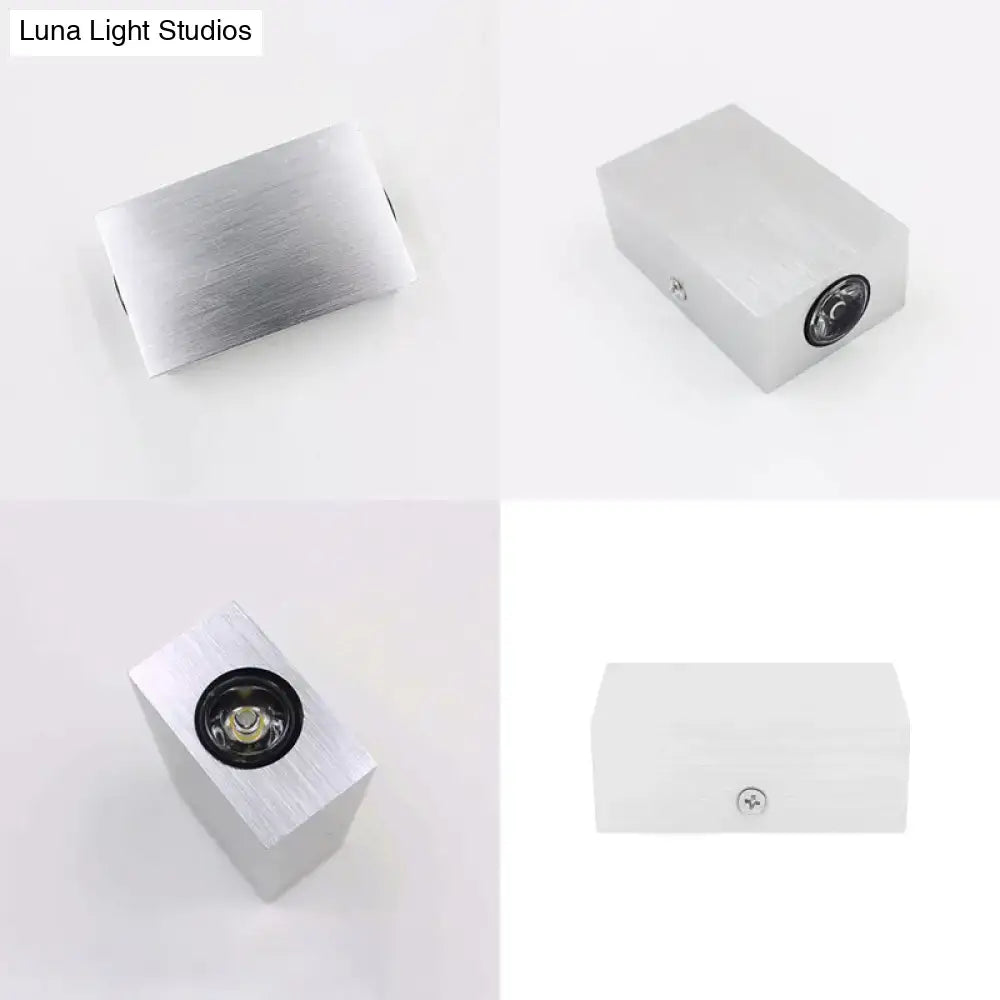 Modern nickel finish rectangular wall sconce with silver brushed aluminum, black circular lens, and visible mounting screw on side