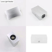 Modern nickel finish rectangular wall sconce with silver brushed aluminum, black circular lens, and visible mounting screw on side