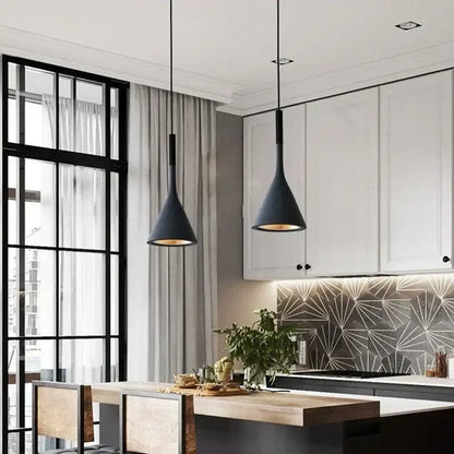 Two sleek black metal modern nordic pendant lights with conical shape and warm brass interior glow hang from ceiling