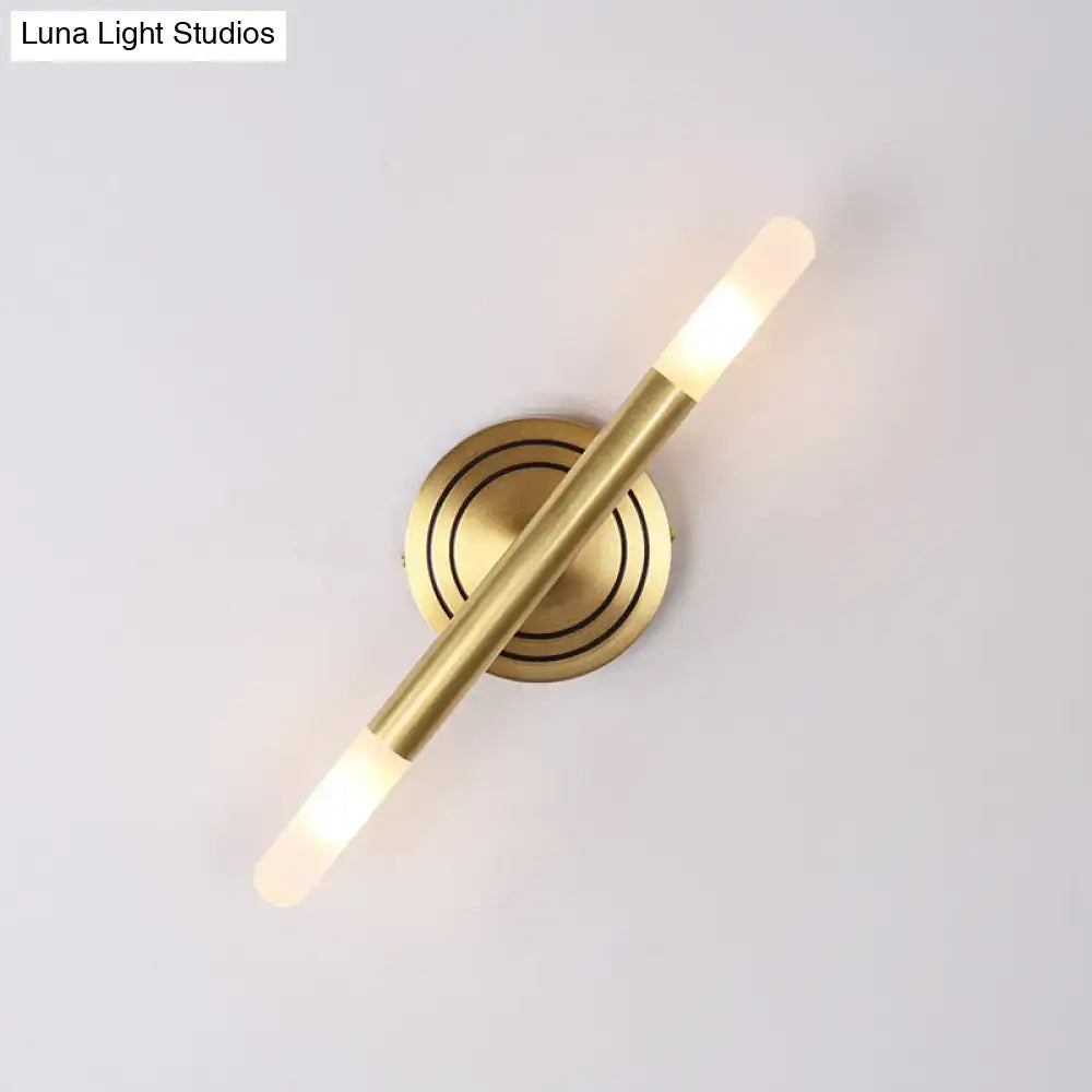 Modern nordic brass finish wall sconce with sleek cylindrical design and frosted glass diffusers emitting warm light