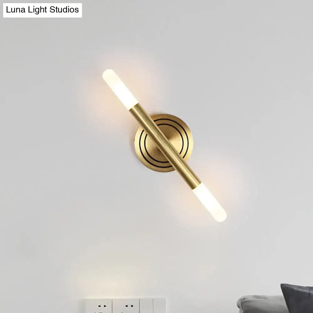 Modern nordic brass finish wall sconce with sleek cylindrical design and two frosted glass light fixtures for bedroom use