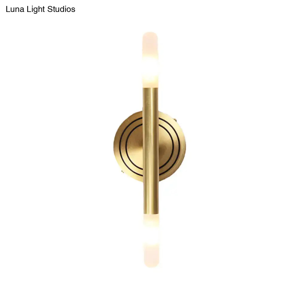 Modern nordic brass finish wall sconce with sleek vertical rod and circular base featuring concentric ring detailing